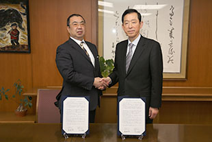 握手を交わす栗林学長（右）と大阪教育大学生協の太田理事長