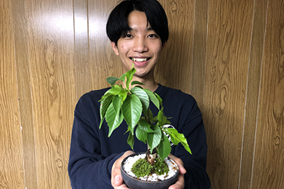 盆栽を手に笑顔の学生