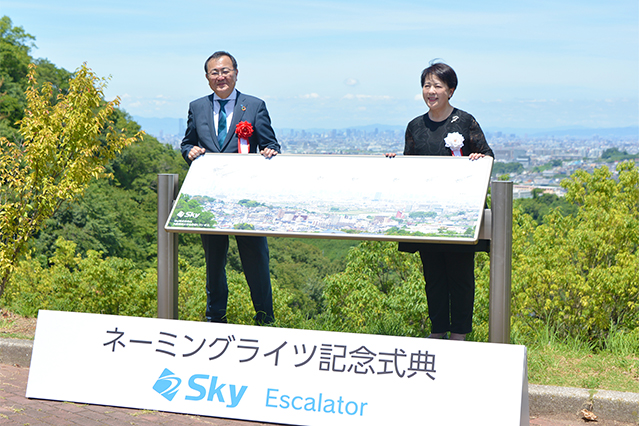 「Sky Escalator」付近の展望台で記念撮影を行う多田昌弘取締役（左）と岡本幾子学長（右）
