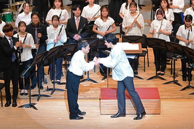 ステージで握手する神代教授とコーニッシュ氏