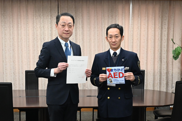 まちかどAED設置施設登録証と標章を手に持つ様子