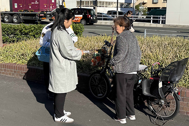 学生が地域住民にビラをわたす様子